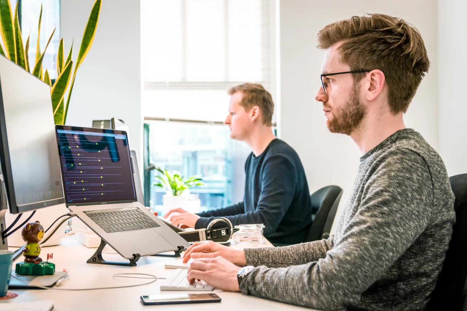 Two colleagues working at desks in a bright office